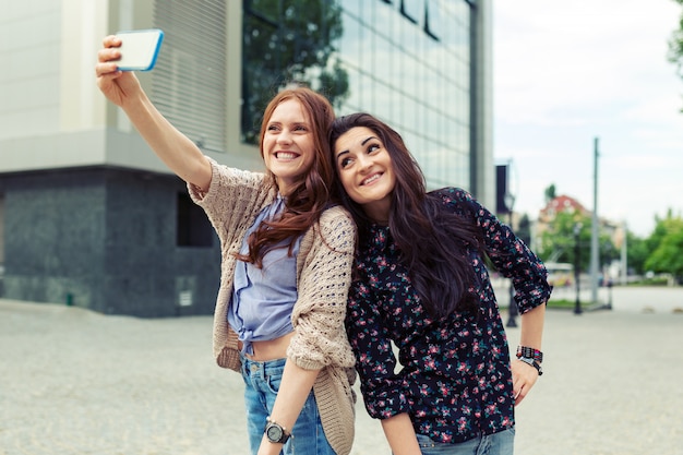 Due ragazze che fanno selfie divertenti per strada, divertendosi insieme