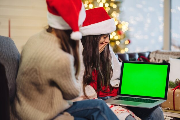 Due ragazze comunicano via Internet con amiche. Computer portatile con schermo verde, chromakey