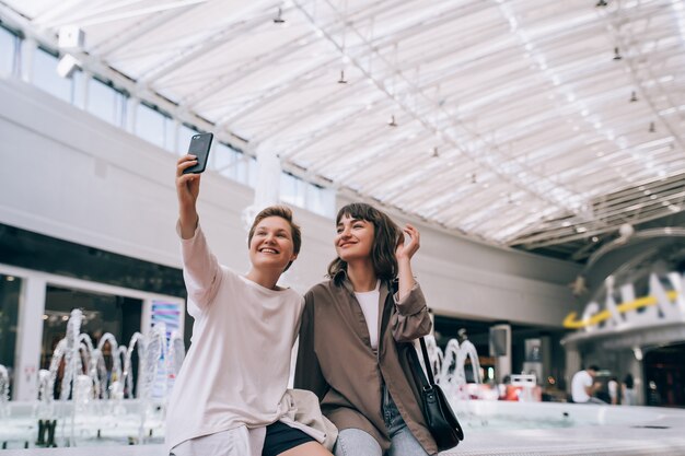 Due ragazze fanno un selfie nel centro commerciale, una fontana