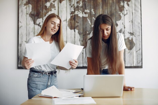 Due ragazze in magliette bianche che lavorano in ufficio