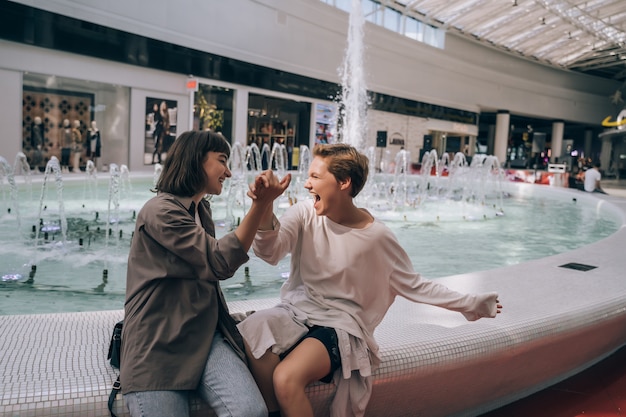 Due ragazze si divertono nel centro commerciale, una fontana