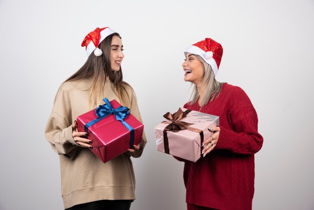 Due ragazze sorridenti in cappello della Santa che tengono i regali di Natale festivi.