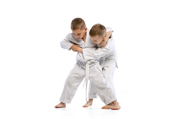 Due ragazzi bambini che combattono allenamento sport marziale karate isolato su sfondo bianco per studio