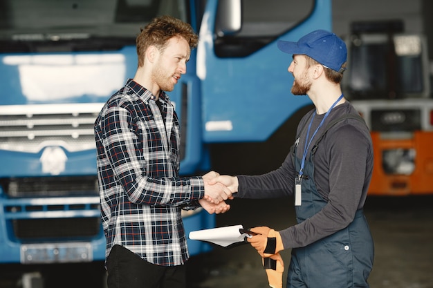 Due ragazzi che parlano di lavoro. Lavora in garage vicino al camion. Trasferimento di documenti con merci