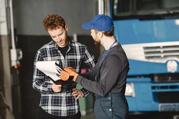 Due ragazzi che parlano di lavoro. Lavora in garage vicino al camion. Trasferimento di documenti con merci