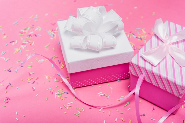 Due scatole regalo decorate e sparse su uno sfondo rosa