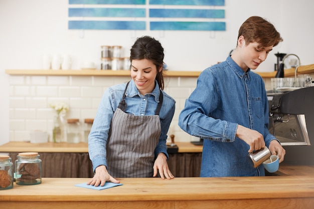 Due simpatici baristi che lavorano al bancone del bar, che sembrano felici.