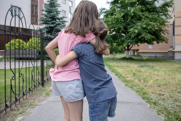 Due sorelline amiche si abbracciano durante una passeggiata in estate