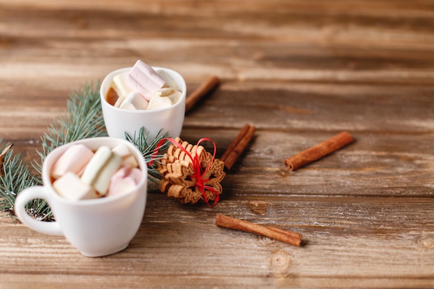 Due tazze con cioccolata calda poggiano su un tavolo con biscotti alla cannella