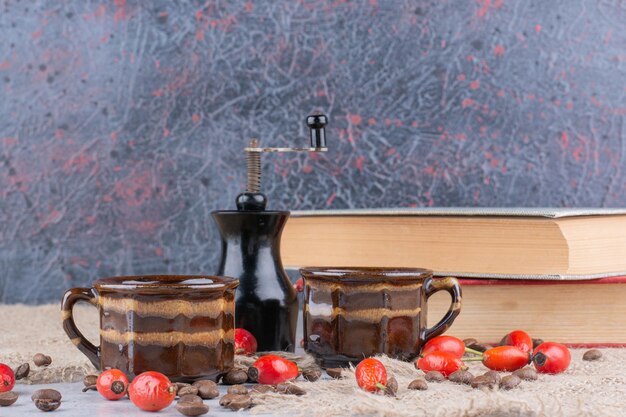 Due tazze di caffè con fagioli e cinorrodi sul tavolo. Foto di alta qualità