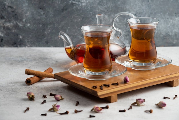 Due tazze di tè di vetro con bastoncini di cannella e rose essiccate.
