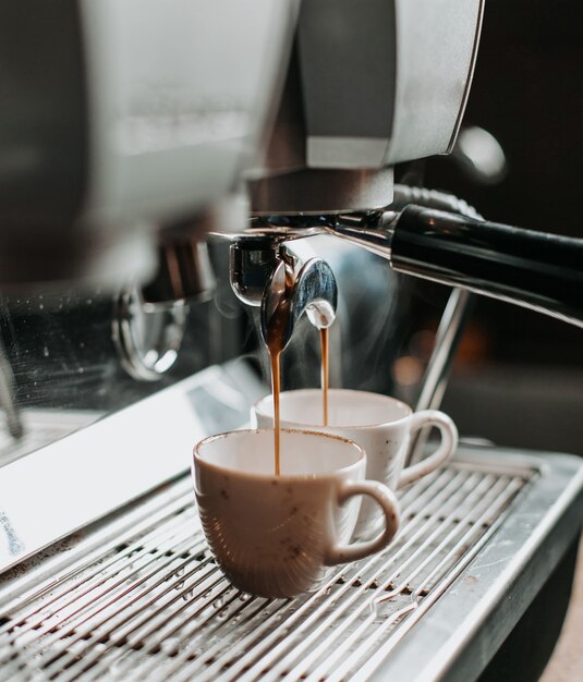 Due tazzine da caffè sotto il motore del caffè