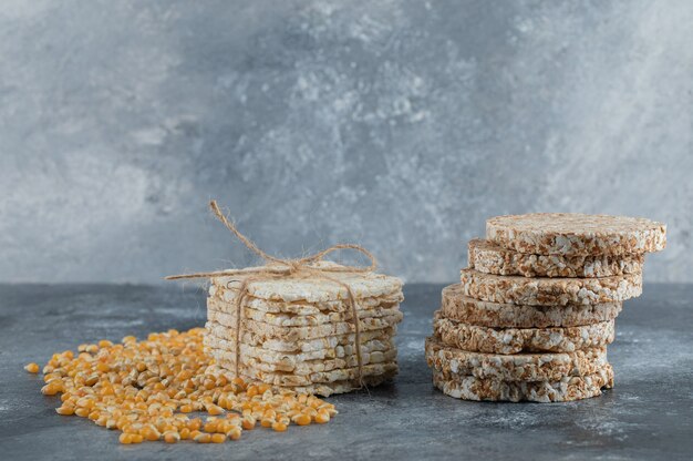 Due tipi di pane croccante e semi di mais crudo su marmo.