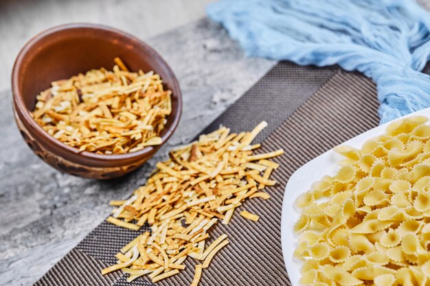 Due tipi di pasta cruda sulla tavola di marmo con panno blu.