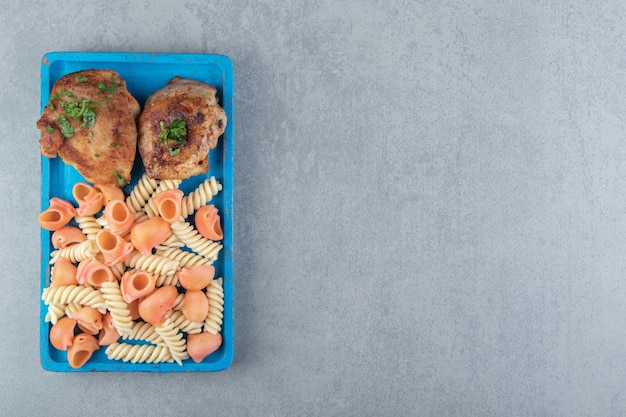 Due tipi di pasta e pollo alla griglia sul piatto blu.