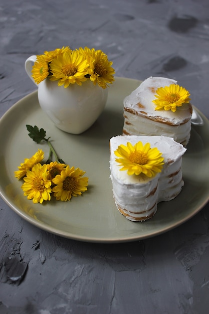 Due torte di miele a forma di cuore con decorazioni di fiori gialli sul piatto di ceramica