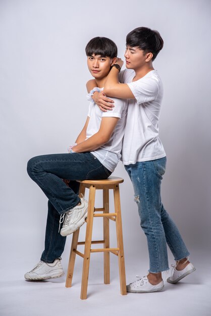 Due uomini che si amano si abbracciano e si siedono su una sedia.