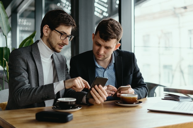 Due uomini d'affari che hanno una conversazione usando uno smartphone