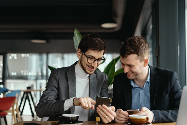 Due uomini d'affari che hanno una conversazione usando uno smartphone