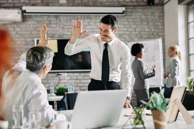 Due uomini d'affari che si congratulano a vicenda per il lavoro di successo e danno il cinque. Focus è sul giovane uomo d'affari