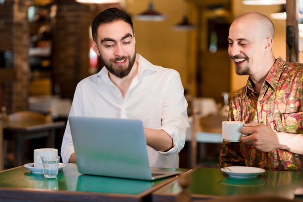 Due uomini d'affari che usano un laptop durante una riunione in una caffetteria. Concetto di affari.