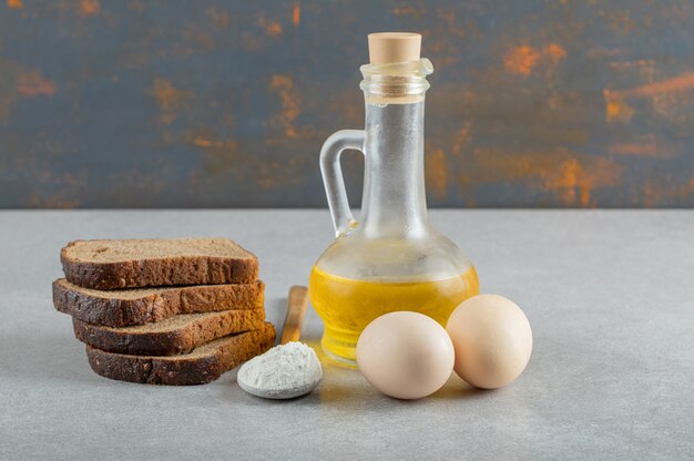 Due uova di gallina con fette di pane e una bottiglia di olio.