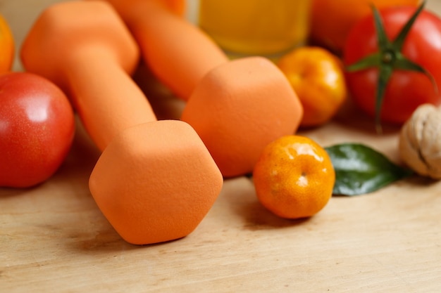 Dumbbell, succo d&#39;arancia, frutta e noci sul tavolo di legno, concetto di stile di vita sport e salute