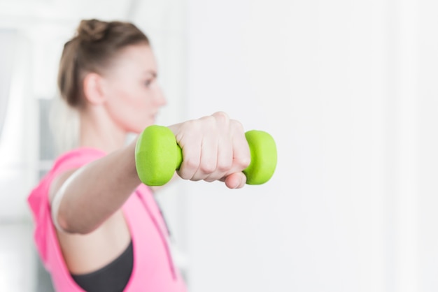 Dumbbell verde sollevato da donna in abbigliamento sportivo