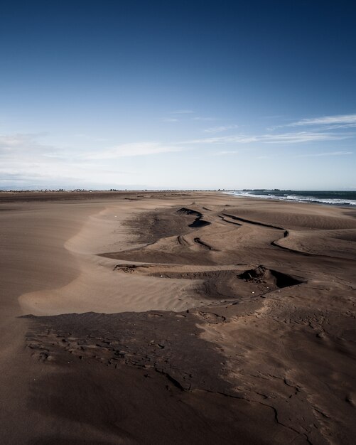 Dune di sabbia marroni in spiaggia sotto il cielo blu