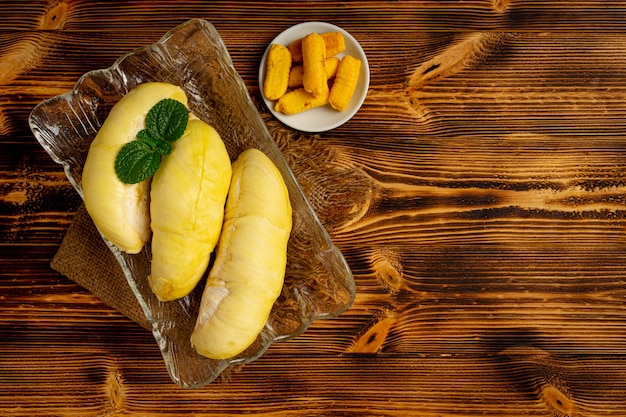 Durian e snack sulla superficie in legno scuro.