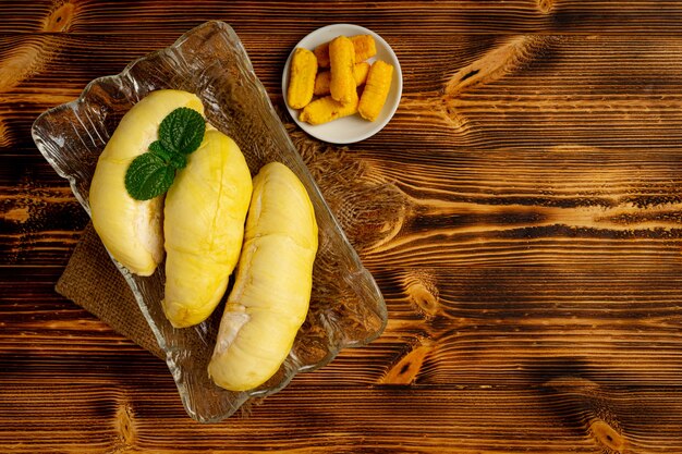 Durian e snack sulla superficie in legno scuro.