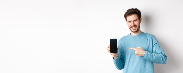 E-commerce e concetto di shopping uomo caucasico sorridente che punta il dito sullo schermo dello smartphone vuoto mostra