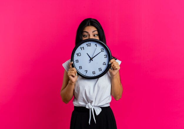 Eccitata giovane donna caucasica tiene e guarda l'orologio