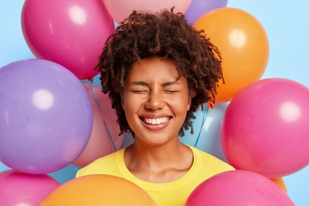 Eccitata giovane donna felicissima in posa circondata da palloncini colorati compleanno