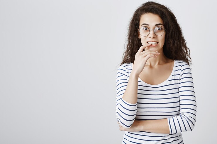 Foto gratuito eccitata ragazza curiosa con gli occhiali che morde il dito e sembra interessata
