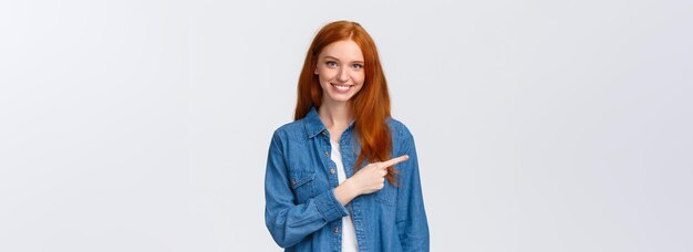 Ecco cosa serve allegra donna rossa in camicia di jeans che punta il dito a sinistra copia spazio sorridente consiglia