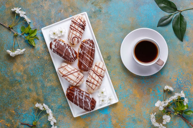 Eclairs o profiteroles con cioccolato nero e cioccolato bianco con crema pasticcera dentro, dessert francese tradizionale vista dall'alto.