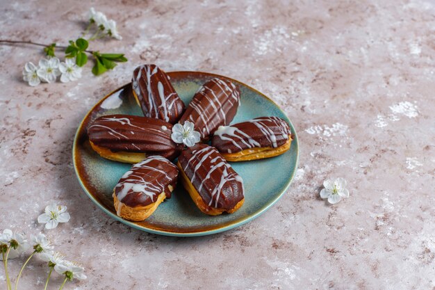 Eclairs o profiteroles con cioccolato nero e cioccolato bianco con crema pasticcera dentro, dessert francese tradizionale vista dall'alto.