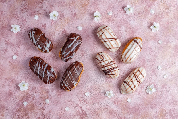 Eclairs o profiteroles con cioccolato nero e cioccolato bianco con crema pasticcera dentro, dessert francese tradizionale vista dall'alto.