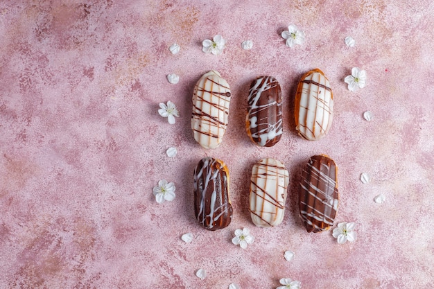 Eclairs o profiteroles con cioccolato nero e cioccolato bianco con crema pasticcera dentro, dessert francese tradizionale vista dall'alto.