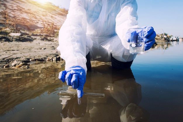 Ecologo che preleva campioni di acqua con provetta dal fiume della città per determinare il livello di contaminazione e inquinamento