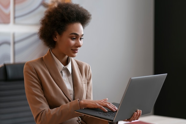 Economista femminile del colpo medio che lavora al computer portatile