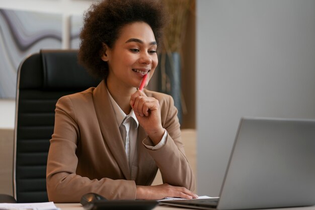 Economista femminile del colpo medio che lavora al computer portatile