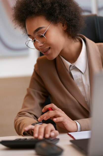 Economista femminile del colpo medio che lavora al computer portatile