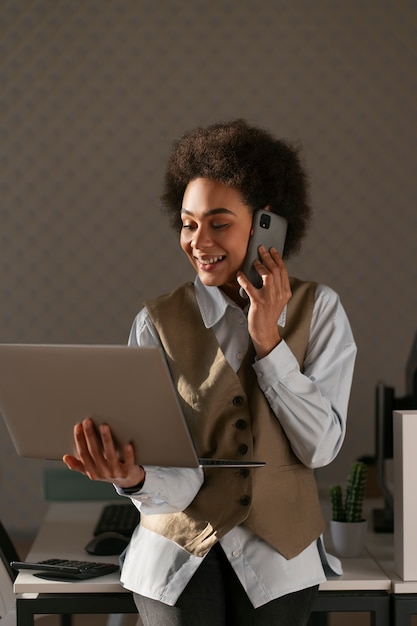 Economista femminile del colpo medio che lavora al computer portatile