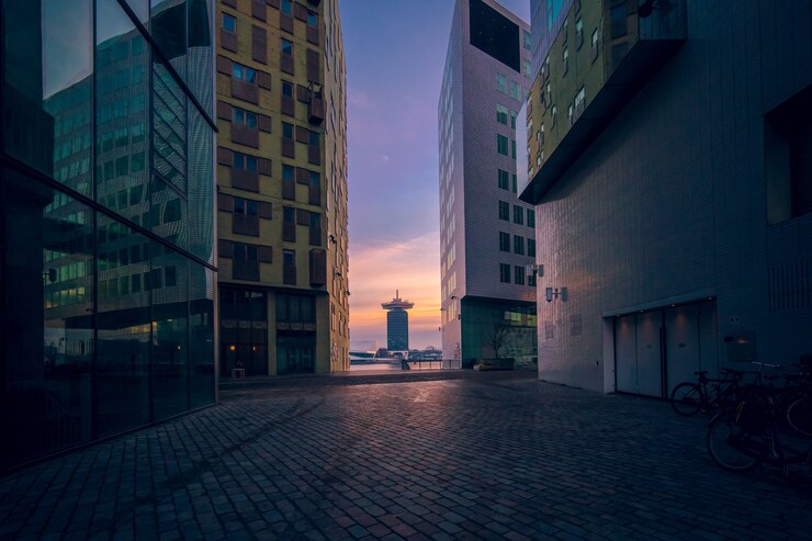 Foto gratuito edifici moderni con finestre di vetro sotto un cielo nuvoloso durante il tramonto la sera