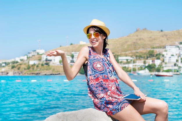 Egli è sorridente donna con gli occhiali da sole e cappello