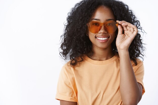 Elegante attraente moderno urbano trendy ragazza dalla carnagione scura che indossa occhiali da sole cool sorridente felice pronto a prendere il sole vicino alla piscina fantastico clima soleggiato che esprime felicità gioia delizia