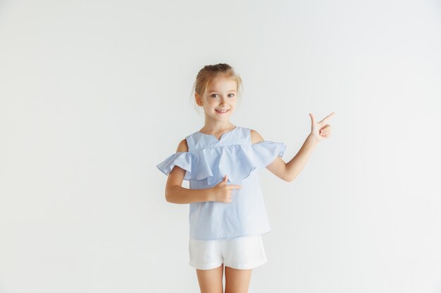 Elegante bambina sorridente in posa in abiti casual isolati su bianco studio