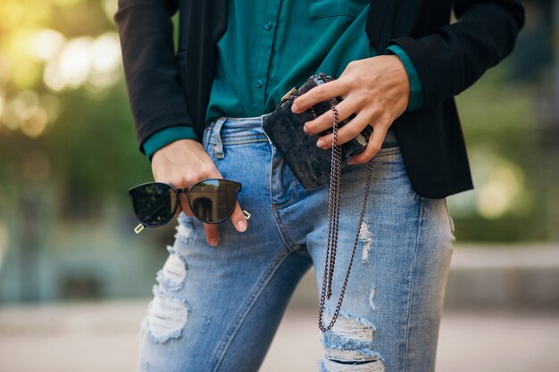 Elegante bella donna in jeans e giacca che cammina in strada con borsetta, stile elegante, tendenze della moda primaverile